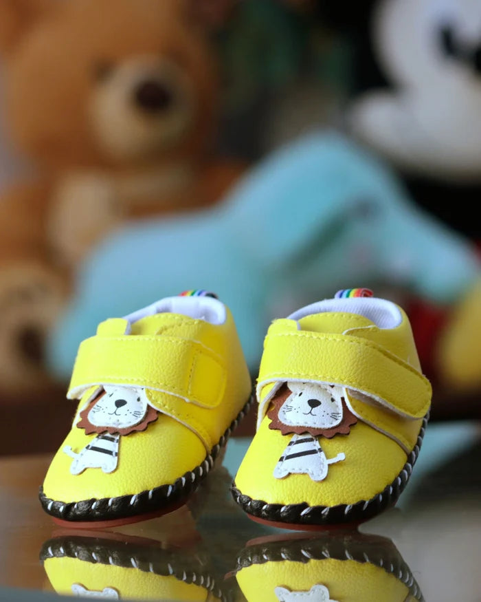 Yellow toddler sandals with adjustable strap and lion face patch, dark sole