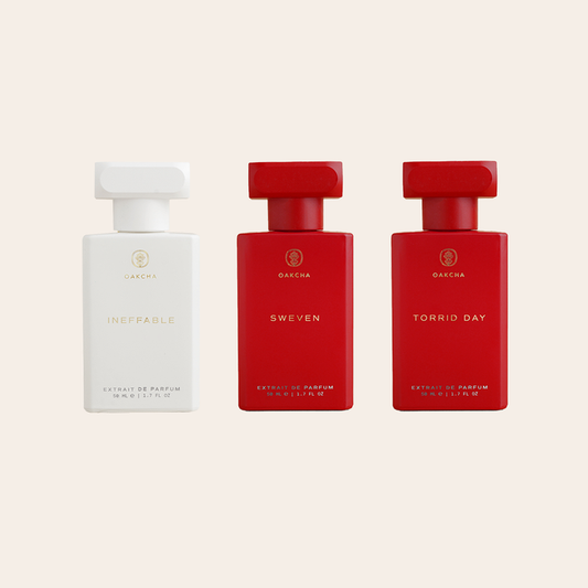 Front view of Best Sellers for Him Bundle, three extrait de parfum bottles, one white and two red, on pale background