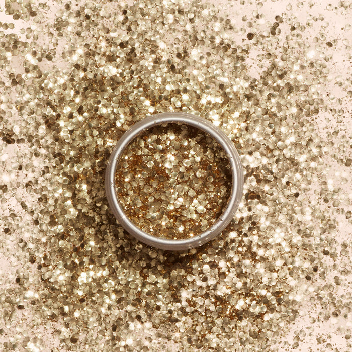 A Manucurist Biodegradable Glitter silver ring sits on a bed of eco-friendly glitter, with gold biodegradable glitter inside, creating a sparkling, festive look.