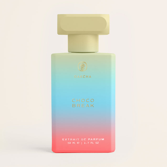 Front view of Choco Break unisex fragrance bottle showcasing blue-to-pink ombre glass, gold logo and pale yellow cap on a light neutral background