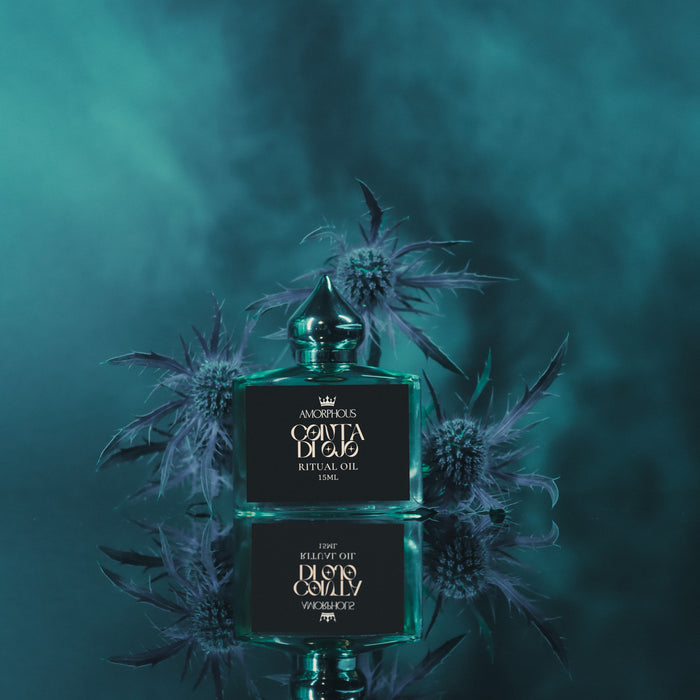 ritual oil bottle with floral design on a dark teal background