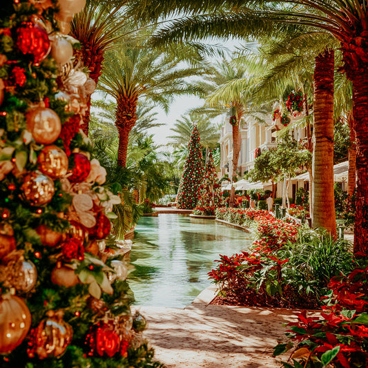 Decorative Christmas trees with ornaments along a palm-lined canal.