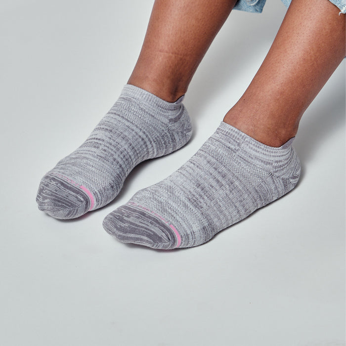 Gray ankle compression socks with a textured pattern and pink accents, worn on bare feet.