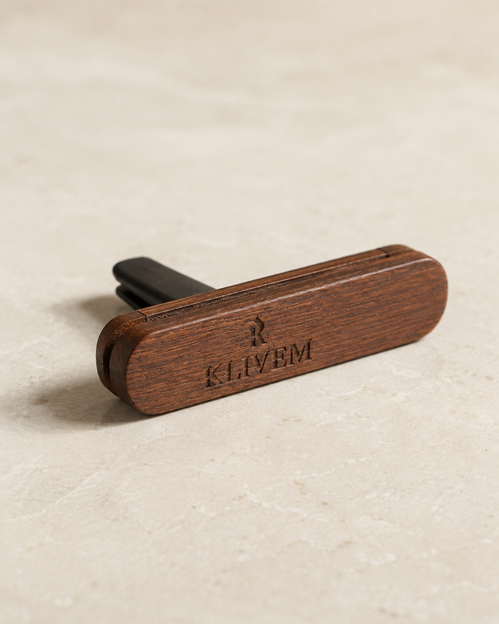 A wooden car key blade cover with the brand name KLIVEM engraved on the front, resting on a light beige textured surface.