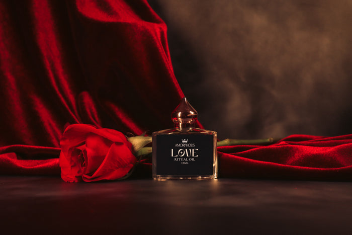 Perfume bottle labeled 'Love Ritual Oil' with red roses on a dark background