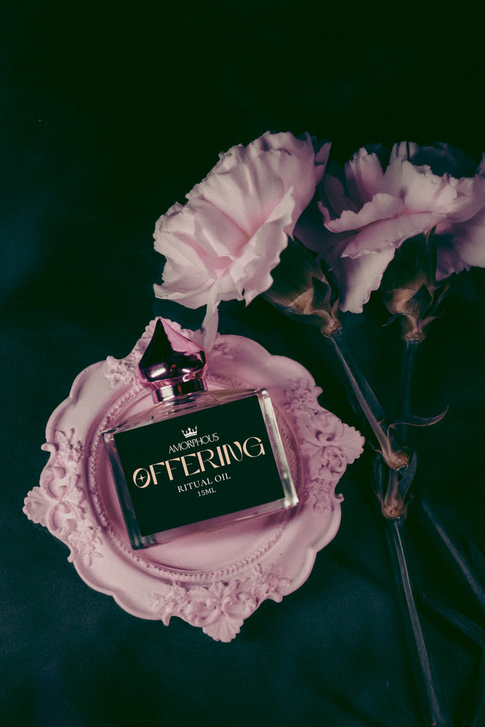 Perfume bottle on a decorative pink stand with flowers in the background