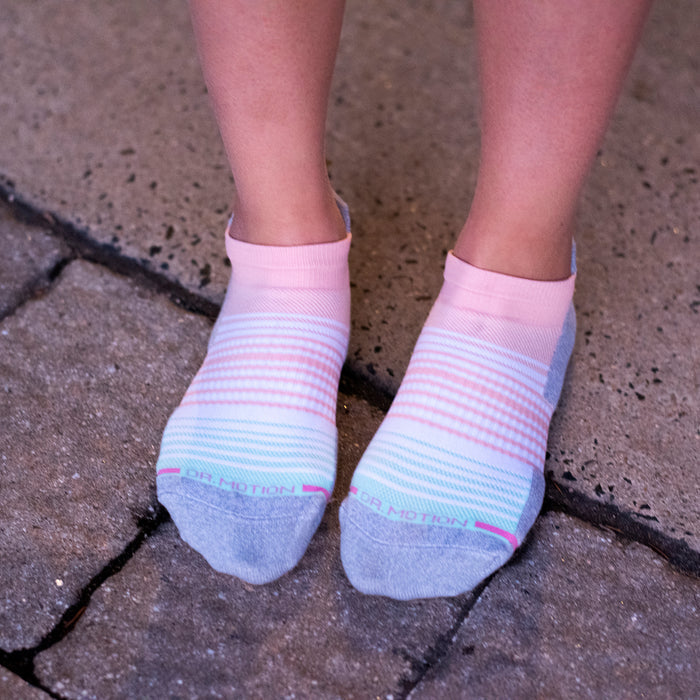 Ankle compression socks with an ombre stripe design in pink and blue, worn on a person's feet.