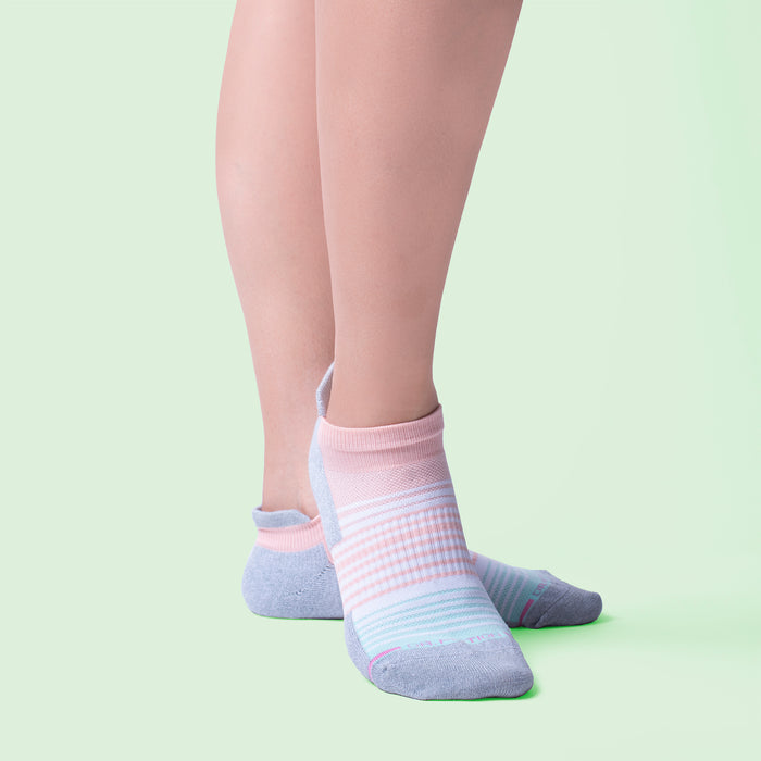 Ankle compression socks with ombre stripe design in pink and blue, worn on bare legs against a light green background.