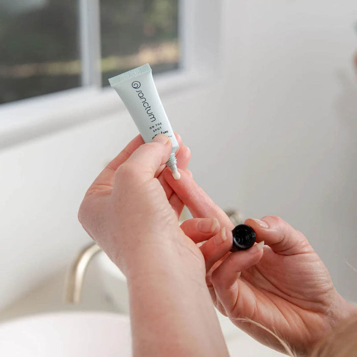 Person holding a skincare product with a blurred background.