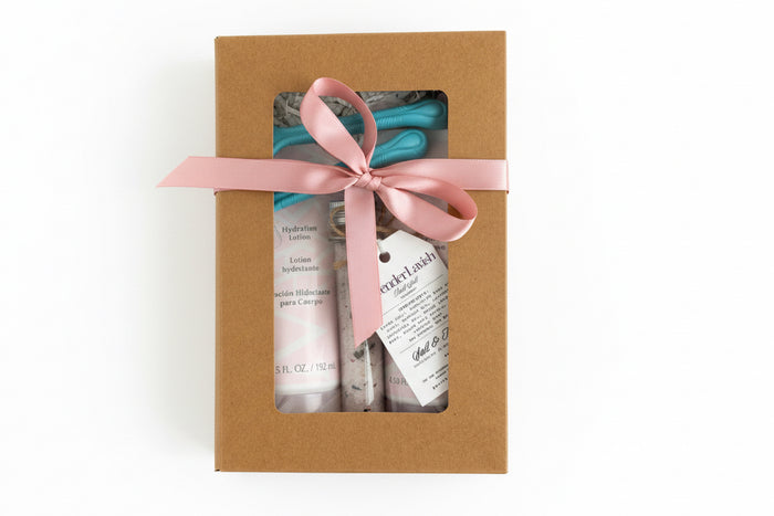Gift set with hand cream and soap in a brown box with a pink ribbon on a gray background