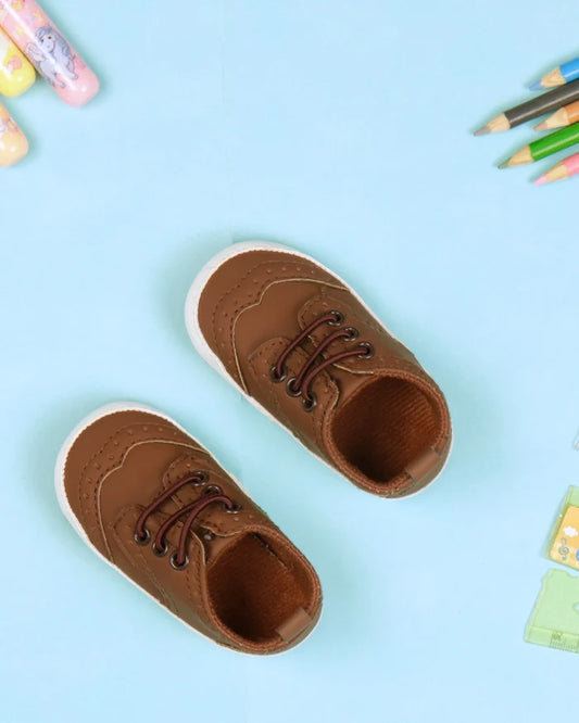 Tan toddler booties with brown lace-up front and white rubber sole