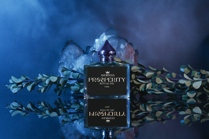 Black bottle of 'Prosperity' ritual oil with a metallic cap on a dark background