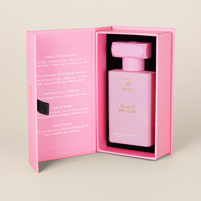 Front view of Silent Melody perfume in pink gift box with gold logo on a pale beige background