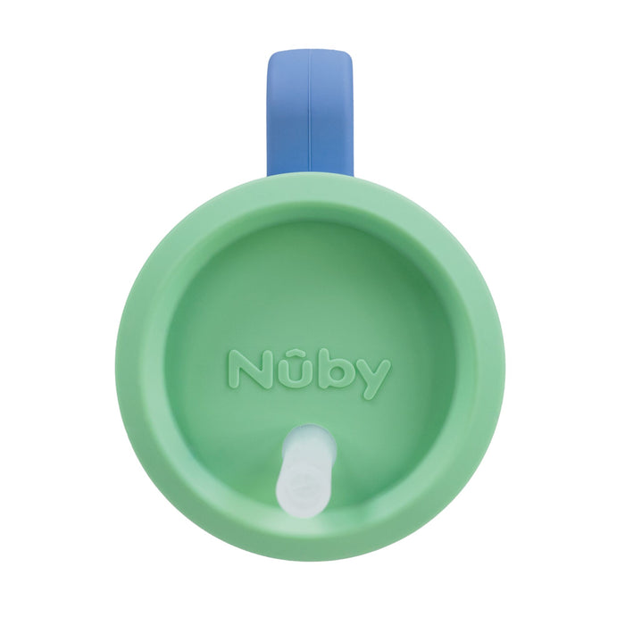 A periwinkle Silicone Tiny Tumbler is shown from above. The Nûby logo is embossed on the lid, and a white spout is visible near the rim.