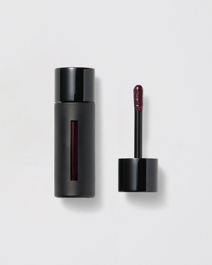 Black lip gloss container with applicator on a gray background
