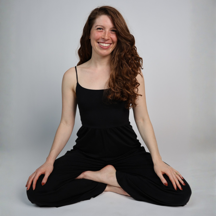SUNDAY RESTORE: Yin Yoga & Sound Bath participant smiling in a meditative pose, embodying peace and wellness.