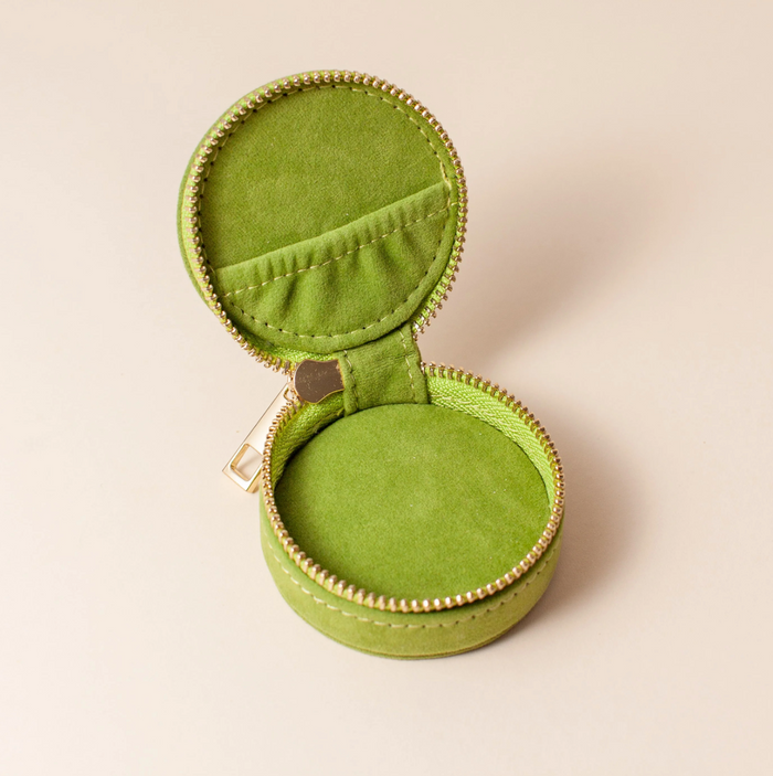 inside the cai and jo Green jewelry box with a gold zipper on a beige background