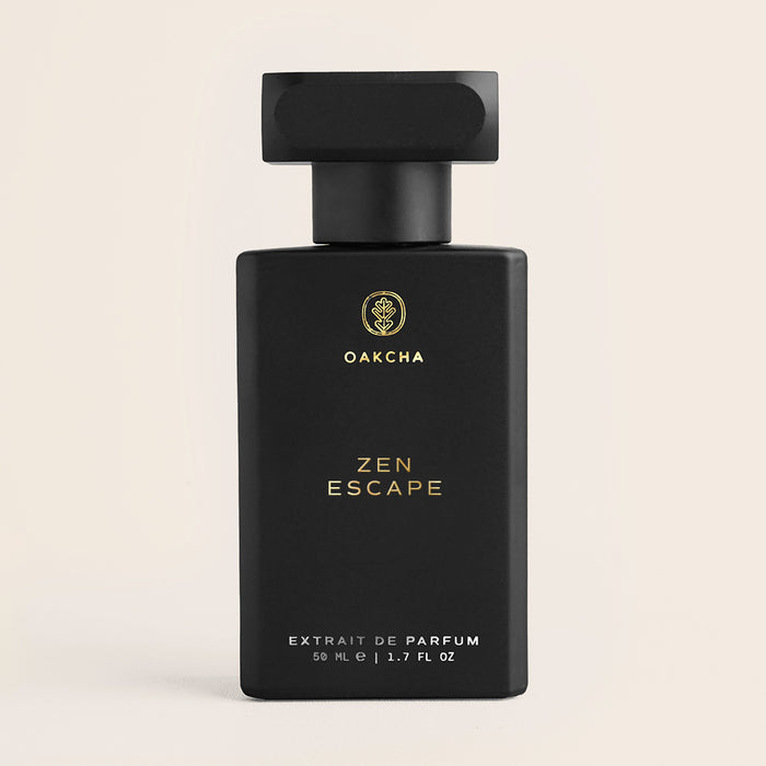Front view of Zen Escape bottle showing matte black rectangular bottle with gold lettering and black cap on pale beige background